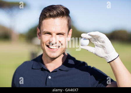 Portrait of cheerful young man showing golf ball Stock Photo
