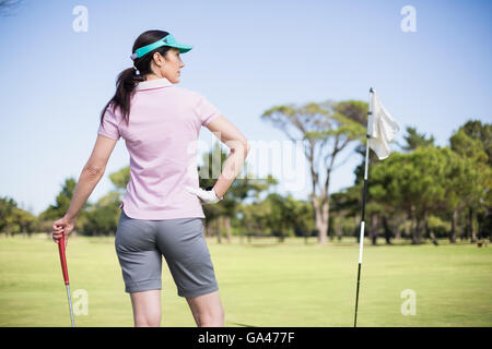 Rear view of woman holding golf club with hand on hip Stock Photo