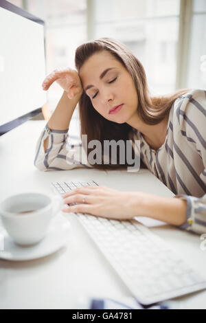 Businesswoman taking nap while working in creative office Stock Photo