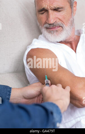 Senior man in pain looking on being vaccinated Stock Photo