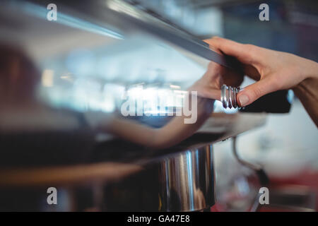 Close-up of barista pushing button on coffee maker at cafeteria Stock Photo