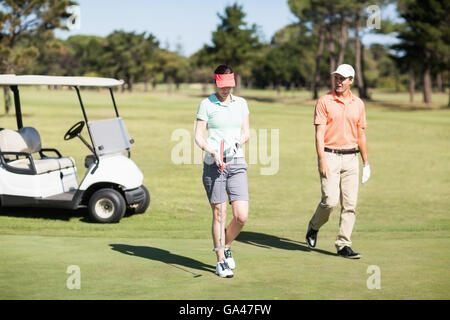 Golfer couple walking on field Stock Photo