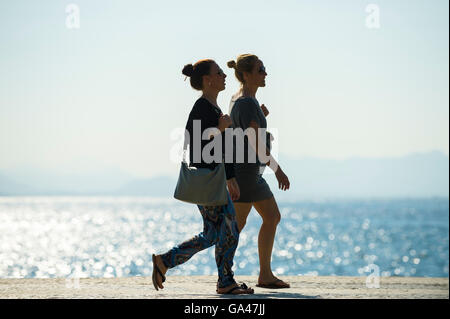 RIO DE JANEIRO - APRIL 3, 2016: Two young Brazilian women walk in silhouette on the boardwalk at Copacabana Beach. Stock Photo