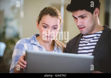Surprised executives looking at laptop in creative office Stock Photo