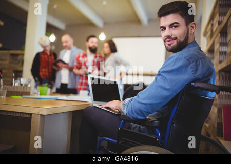 Smart disabled businessman using laptop at desk Stock Photo