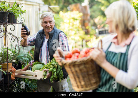 Male gardener with vegetables looking at woman Stock Photo