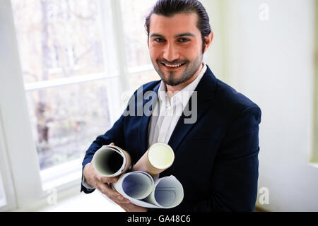 Happy interior designer holding blueprints Stock Photo