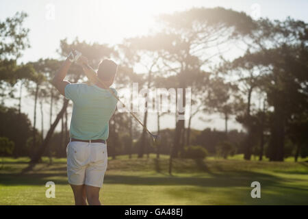 Rear view of young golfer taking shot Stock Photo