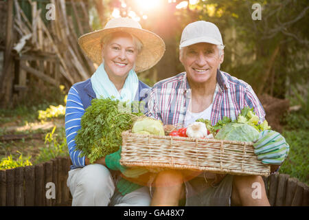 Portrait of mature couple carrying vegetables crate at garden Stock Photo