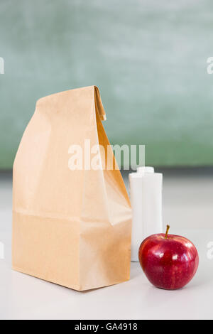 Apple with drink bottle and paper bag on table Stock Photo