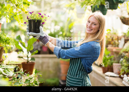 Portrait of female gardener holding flowering plant Stock Photo