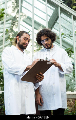 Male scientists discussing over clipboard Stock Photo