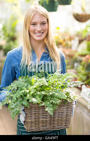 Beautiful woman holding plant in wicker basket Stock Photo
