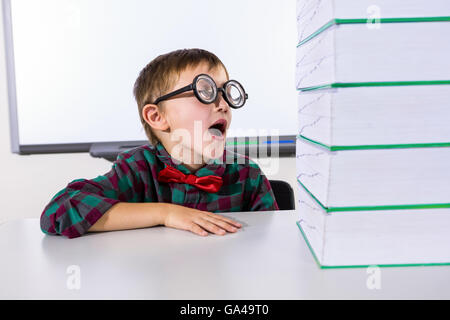 Surprised boy by stacked books in classroom Stock Photo