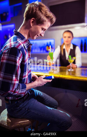 Man using mobile phone with bartender standing Stock Photo