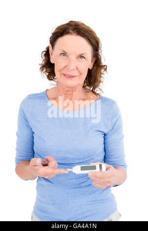 Portrait of smiling mature woman using blood glucose monitor Stock Photo