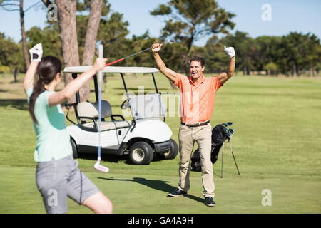 Happy golfer couple with arms raised Stock Photo