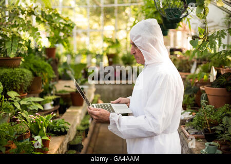 Male scientist in clean suit using laptop Stock Photo