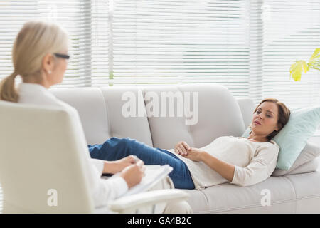 Woman lying on sofa while talking to therapist Stock Photo
