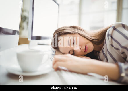 Tired businesswoman taking nap in creative office Stock Photo
