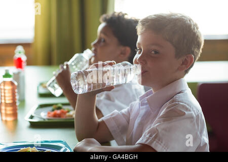 Portrait of schoolboy drinking water from bottle Stock Photo