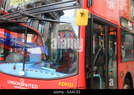 Union Jack flags reflected in a red London bus's window in the West End, on Oxford Street, in England, UK Stock Photo