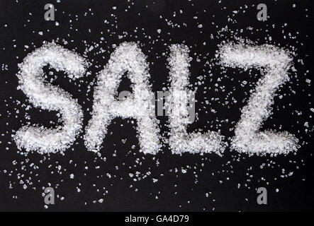 Coarse-grained sea salt with the German word SALZ on black background Stock Photo
