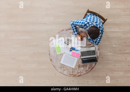 Man working on a wooden table with laptop and financial documents, top view Stock Photo