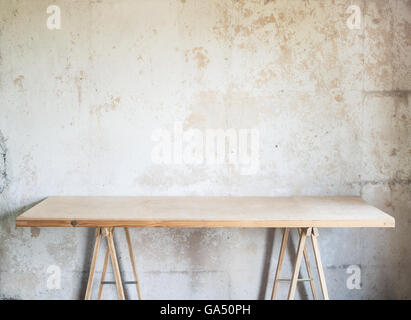 Wooden workshop table against concrete wall. Stock Photo