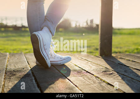 woman's legs in trainers against the sunset Stock Photo