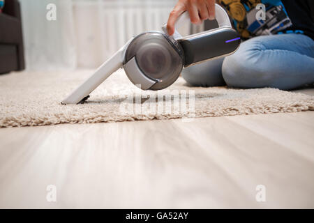 Cleaning of rug in house portable rechargeable vacuum cleaner Stock Photo