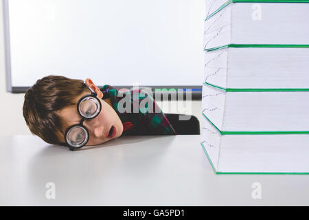Stressed boy by stacked books on table Stock Photo