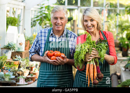 Gardeners holding fresh vegetables at greenhouse Stock Photo