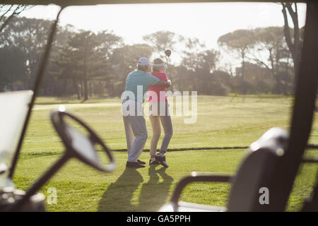 Rear view of mature man teaching woman to play golf Stock Photo