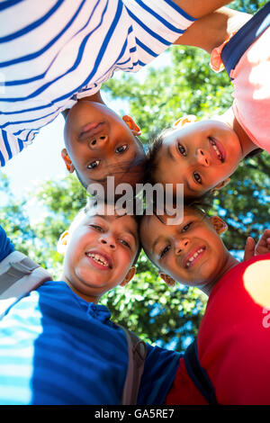 Low angle portrait of happy children forming huddle Stock Photo