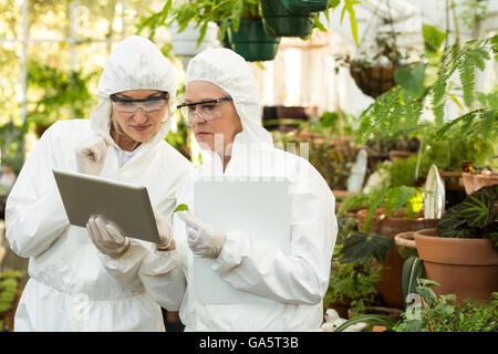 Scientists in clean suit discussing over digital tablet Stock Photo