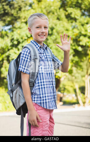 Happy schoolkid waving hand in campus Stock Photo