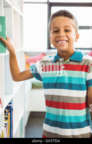 Boy taking a book from bookshelf in library Stock Photo