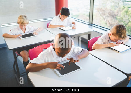 Schoolkids using digital tablets in classroom Stock Photo