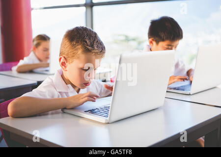 Schoolkids using laptop in classroom Stock Photo