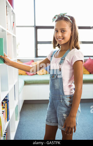 Girl taking a book from bookshelf in library Stock Photo