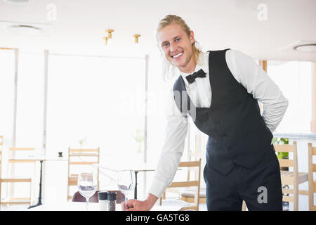 Waiter standing at table with empty glass Stock Photo