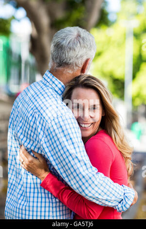 Mature woman hugging man by tree Stock Photo