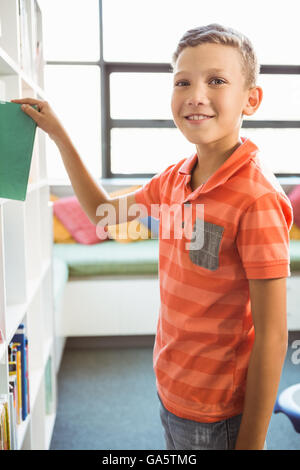 Boy taking a book from bookshelf in library Stock Photo