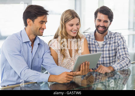 Smiling woman and two men using digital tablet Stock Photo