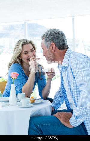 Smiling mature woman feeding food to man Stock Photo