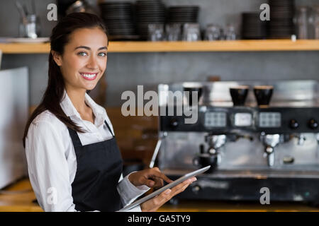 Portrait of smiling waitress using digital tablet Stock Photo