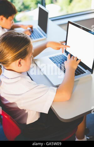 Schoolkids using laptop in classroom Stock Photo