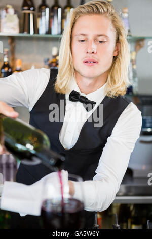 Waiter pouring wine into glass Stock Photo