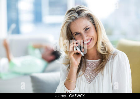Smiling woman using mobile phone at home Stock Photo